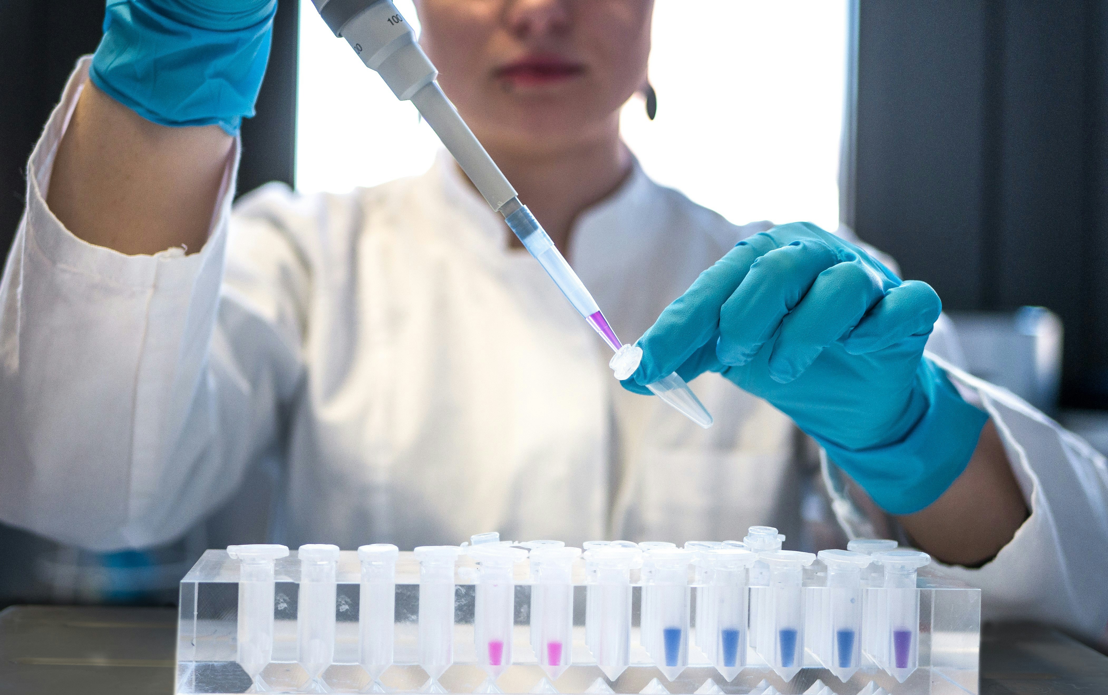 Female scientist in lab wearing blue surgical gloves